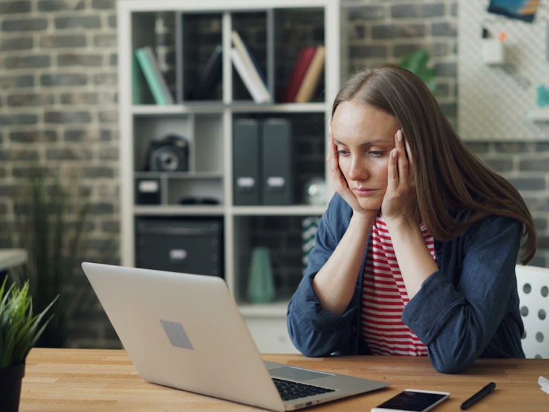 no trabalho palestra saude da mulher para empresas Mulher no trabalho, diante do computador, com expressão de cansaço e desconforto